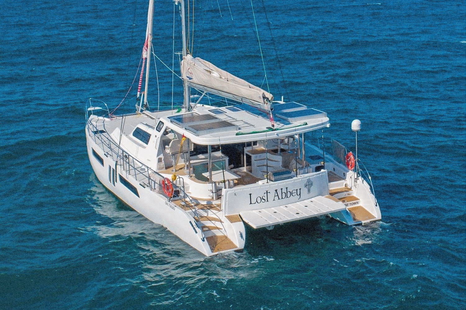 Lost Abbey underway, seen from behind with her twin hulls in deep blue water