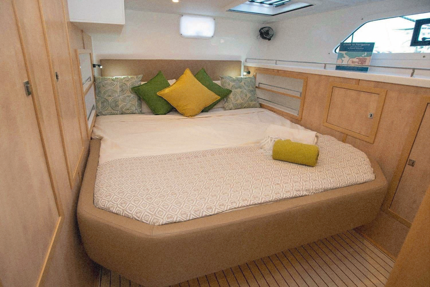 A guest cabin with a wide bed and green and yellow cushions