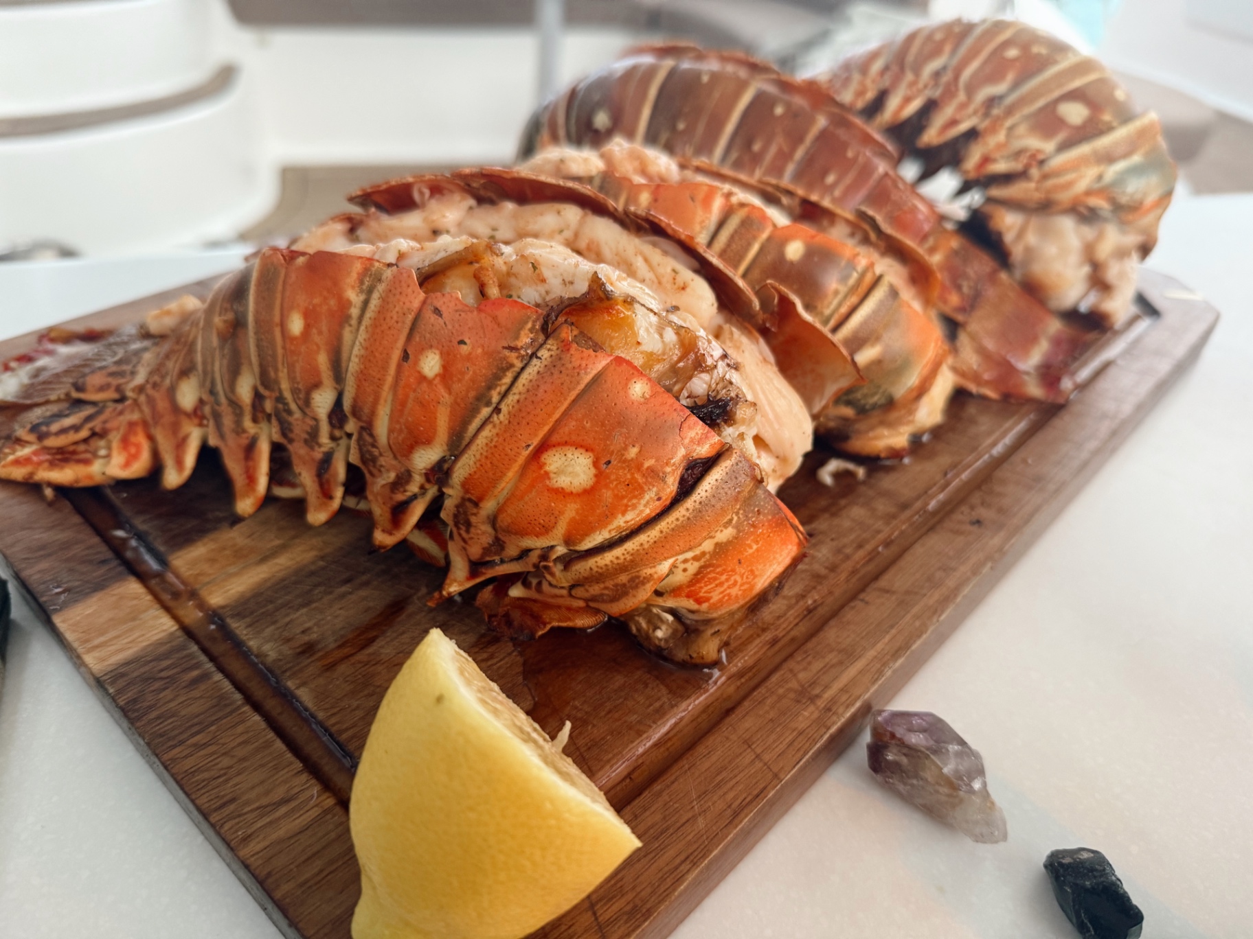 Fresh lobster tails on a wooden board with a lemon wedge